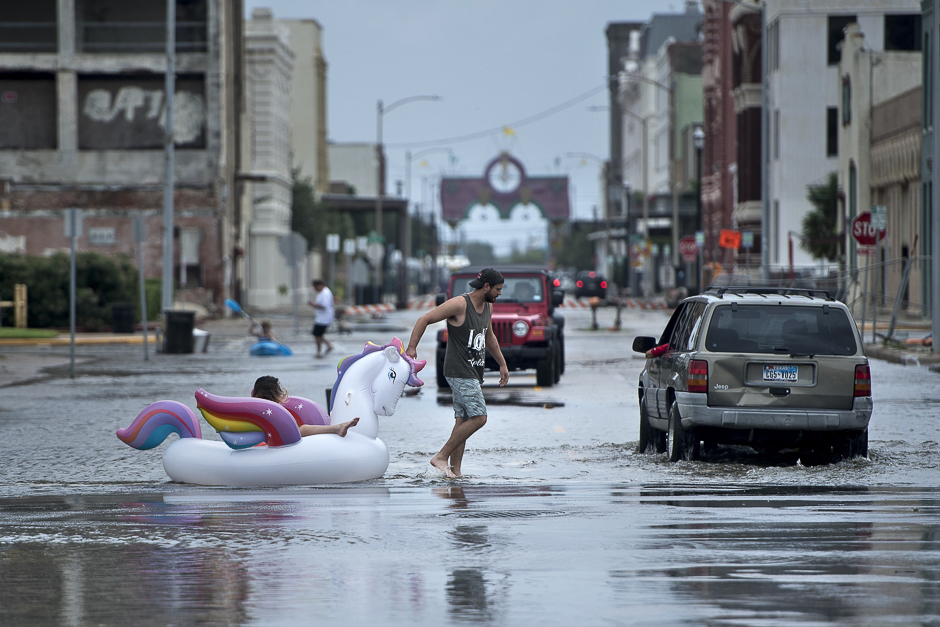 People make their way down partially flooded roads following the passage of Hurricane Harvey in Galveston, Texas. PHOTO: AFP