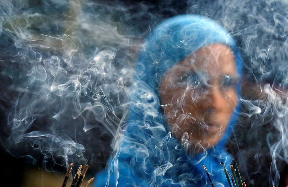 Smoke rises from burning incense sticks as a woman prays inside the shrine of Muslim Sufi Saint Nizamuddin Auliya in New Delhi, India. PHOTO: REUTERS