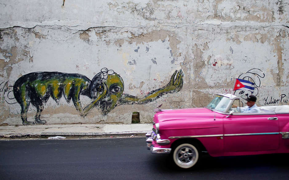 A vintage car passes by a graffiti of Cuban Artist Yulier Rodriguez in Havana, Cuba. PHOTO: REUTERS