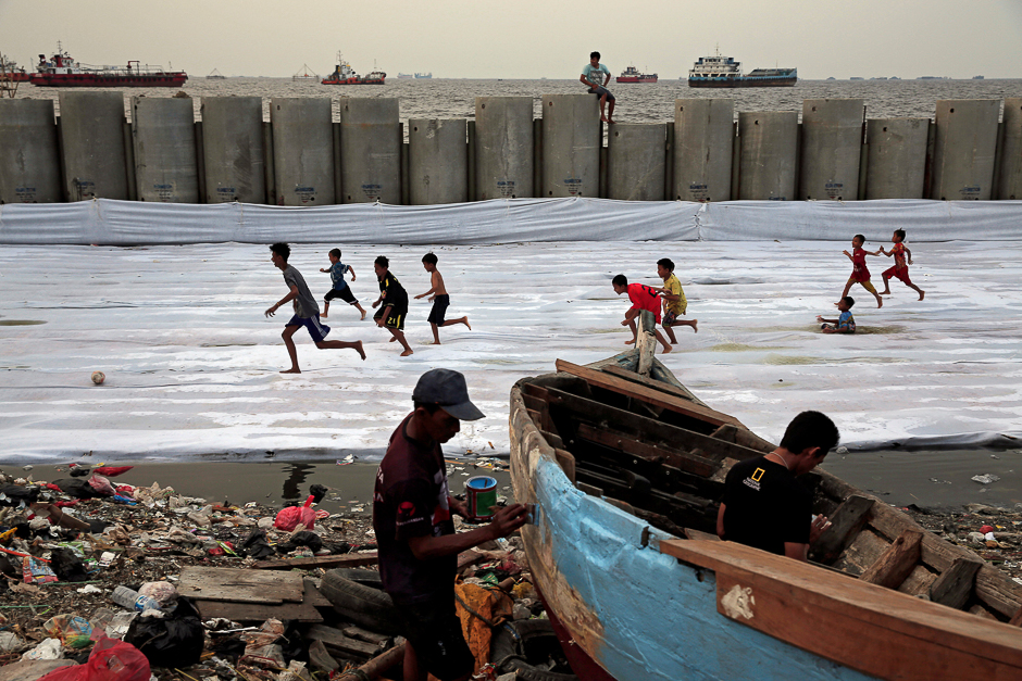 Children play soccer as fisherman paints his boat near breakwater at Cilincing area in Jakarta, Indonesia. PHOTO: REUTERS