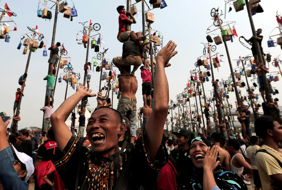 A couple reacts as their colleague wins a bicycle during greased pole competition during the celebration of Independence Day in Jakarta, Indonesia. PHOTO: REUTERS