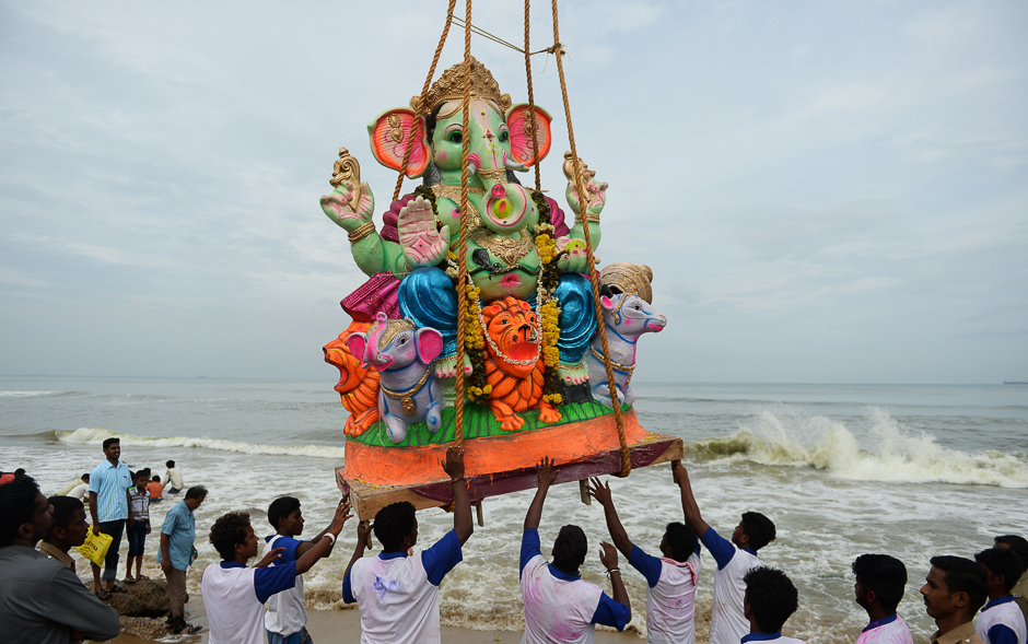 Indian devotees hold an idol of elephant-headed Hindu god Ganesha as it is lifted by a crane before immersing it in the Indian ocean at Pattinapakkam beach in Chennai. PHOTO: AFP