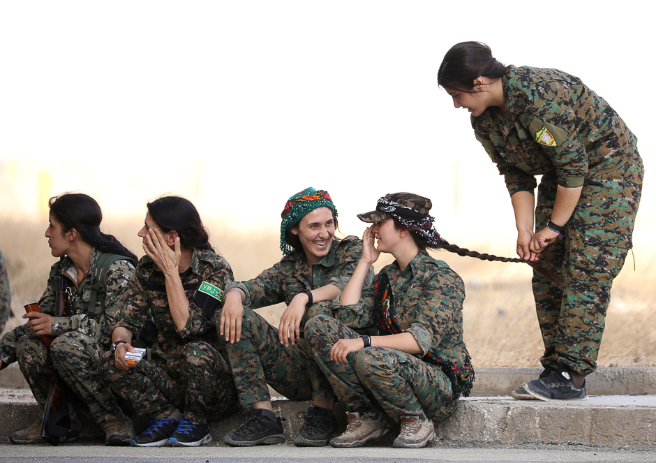 Syrian Democratic Forces (SDF) female fighters sit together on a curb in the city of Hasaka, northeastern Syria. PHOTO: REUTERS