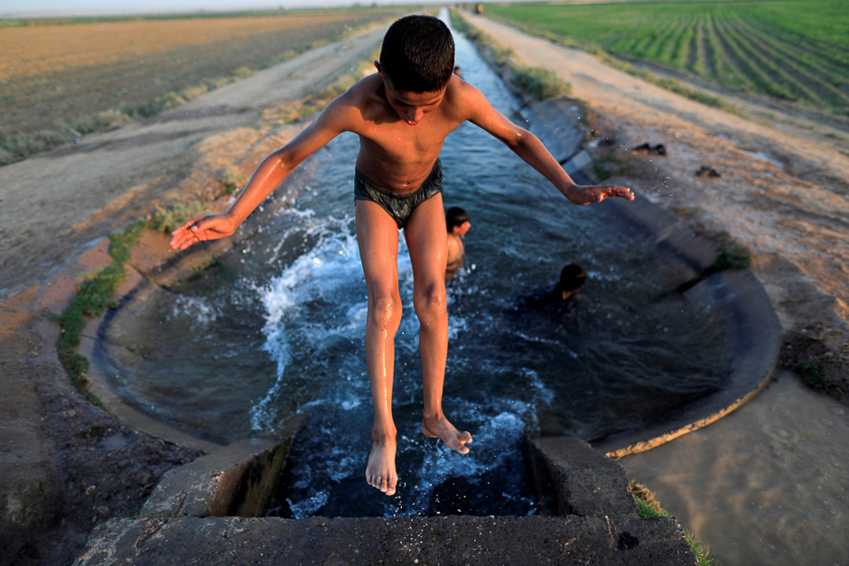 A boy cools off in an irrigation canal on the outskirts of Raqqa, Syria. PHOTO: REUTERS