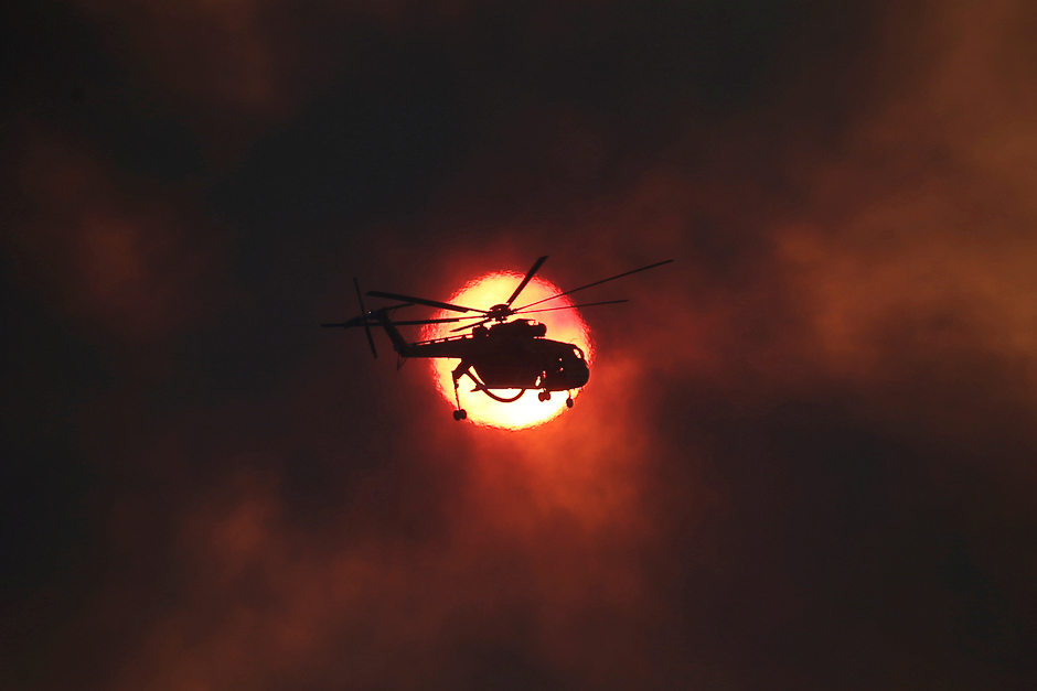 A firefighting helicopter flies in front of the setting sun as a wildfire burns near the village of Kapandriti, north of Athens, Greece. PHOTO: REUTERS