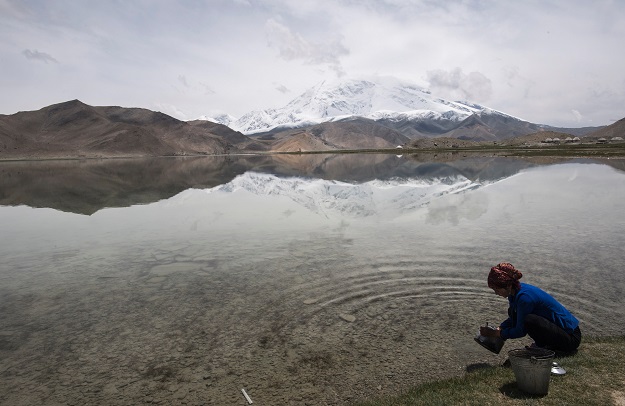 A woman collects water from the Karakul Lake before the Karakorum mountain range next to the China-Pakistan Friendship Highway, near Tashkurgan in China's western Xinjiang province. PHOTO: AFP