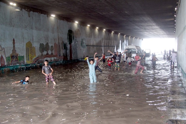 Children play in the water accumulated in the Liaquatabad Underpass. PHOTO: EXPRESS