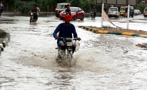 A motorcyclist travels through water on a main thoroughfare of the city. Many areas were submerged after the rain. PHOTO: EXPRESS