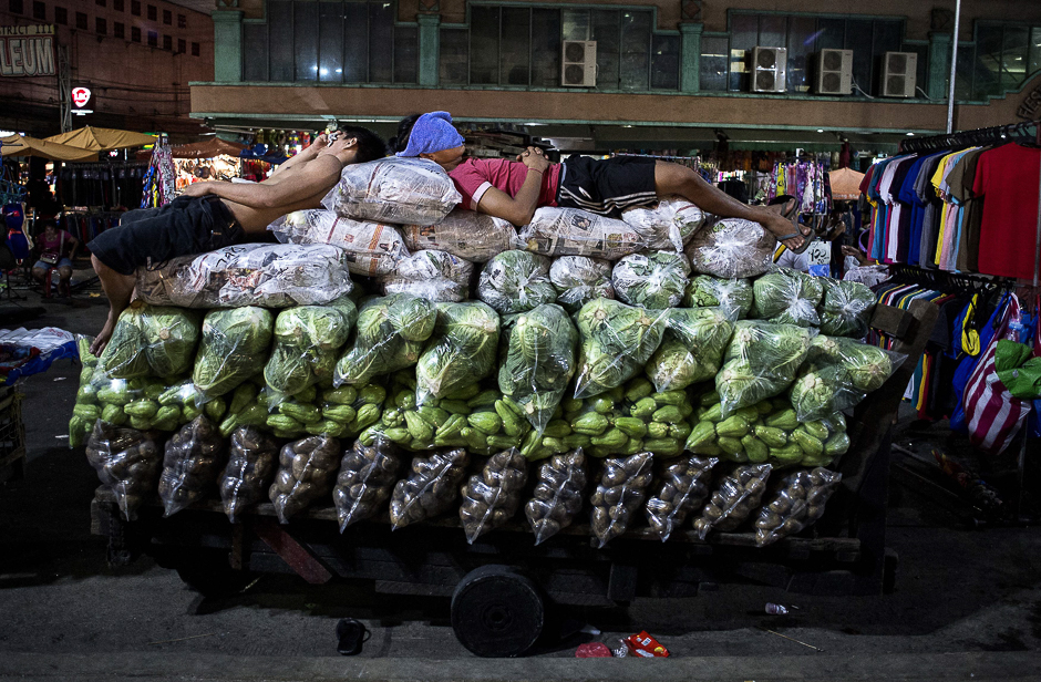 Workers sleep on top of vegetables on a wooden cart in Divisoria market in Manila. PHOTO: AFP