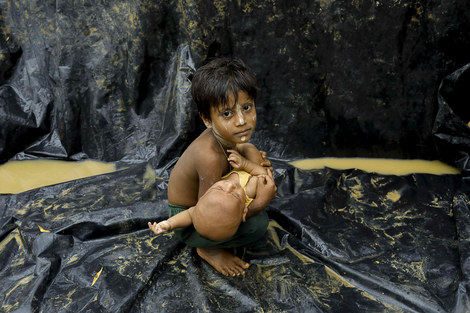 A Rohingya refugee from Myanmar's Rakhine state holds a baby after arriving at a refugee camp near the Bagladeshi town of Teknaf. PHOTO: AFP