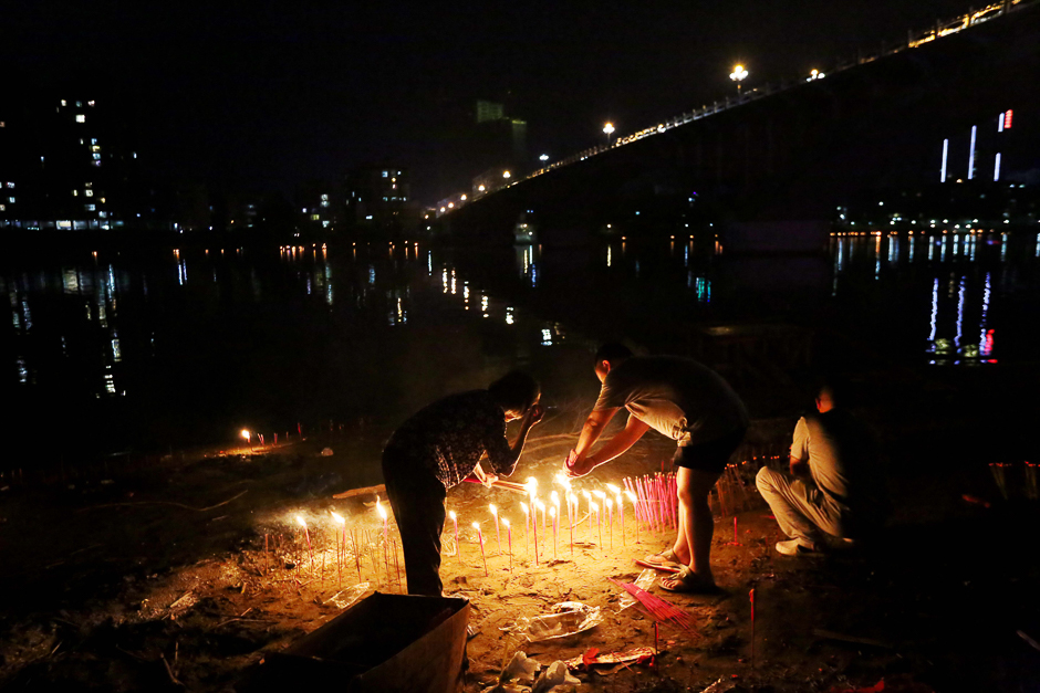 Local residents burning paper offerings as a ritual for deceased ancestors during the Zhongyuan Festival, on the waterfront of the Rongjiang River in Rongan. PHOTO: AFP