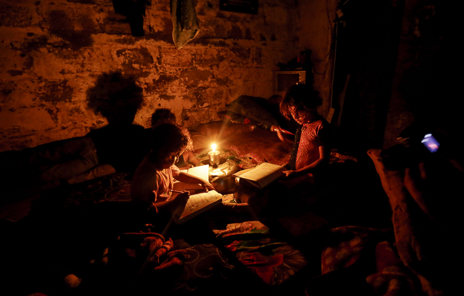 Palestinian children do their homeworks during a power cut in an impoverished area in Gaza City. PHOTO: AFP