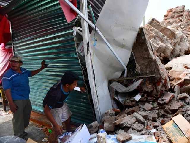 Survivors station nearby a rubble of a building in Juchitan de Zaragoza after it was broken by Mexico's misfortune trembler in over a century. PHOTO: AFP