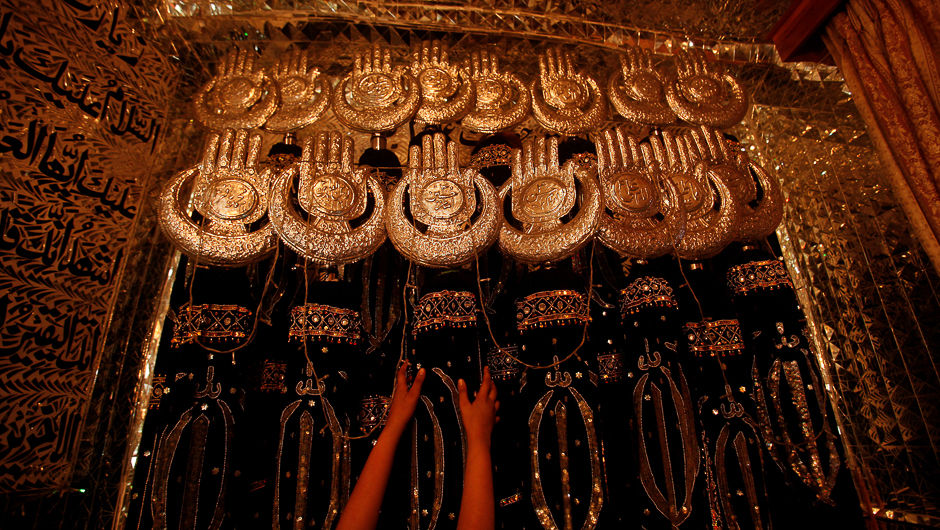 A girl reaches for a religious symbol religious symbols at an Imam Bargah ahead of Ashura in Peshawar, Pakistan. PHOTO: REUTERS