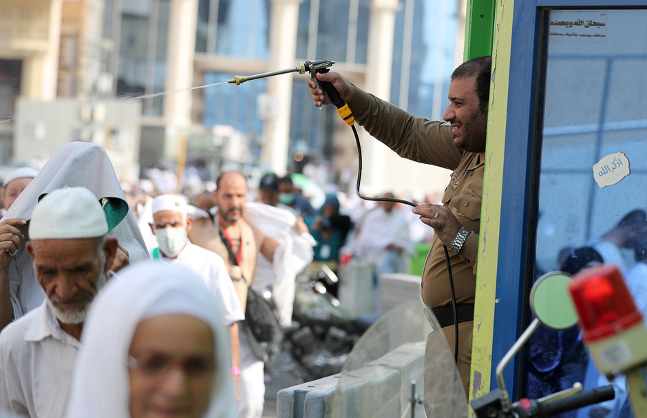 Saudi security personel spray water on pilgrims to cool them off. PHOTO: AFP