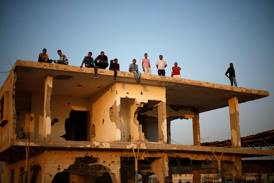 Palestinians gather atop a damaged building as they wait for the return of their relatives after performing the annual Haj pilgrimage in Mecca, at Rafah border crossing, in the southern Gaza Strip. PHOTO: REUTERS