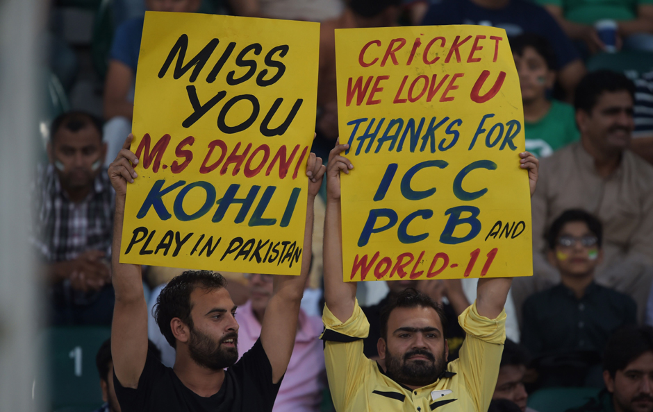 6.Pakistani spectators hold placards at the Gaddafi Cricket Stadium in Lahore. PHOTO: AFP