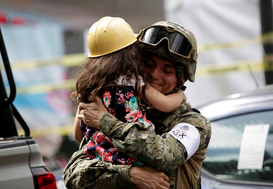A girl hugs a Mexican marine officer as she offers hugs to people near the site of a collapsed building after an earthquake, in Mexico City, Mexico. PHOTO: REUTERS