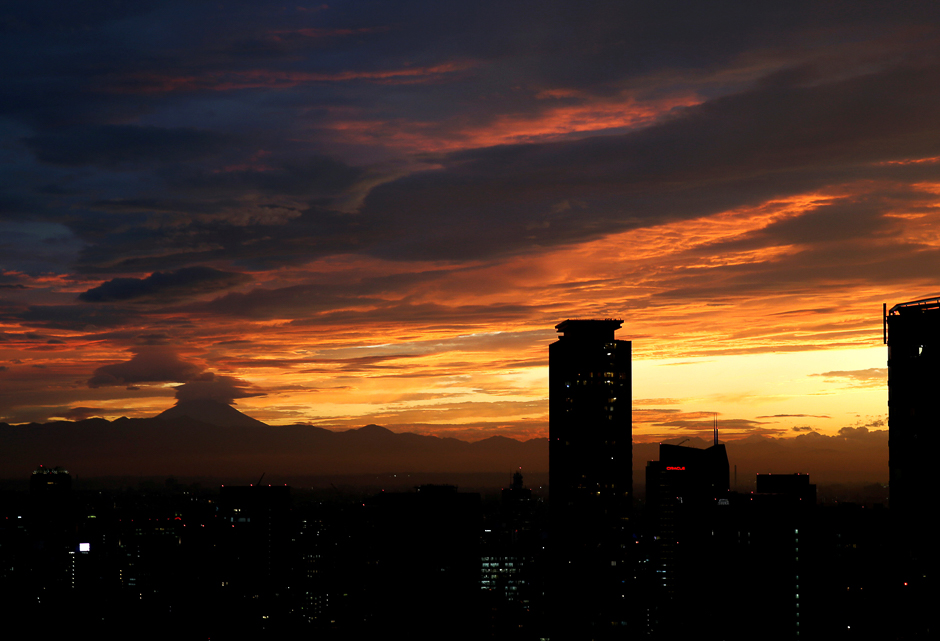 The silhouette of Japan's highest mountain Mount Fuji is seen beyond buildings in the dusk in Tokyo, Japan. PHOTO: REUTERS