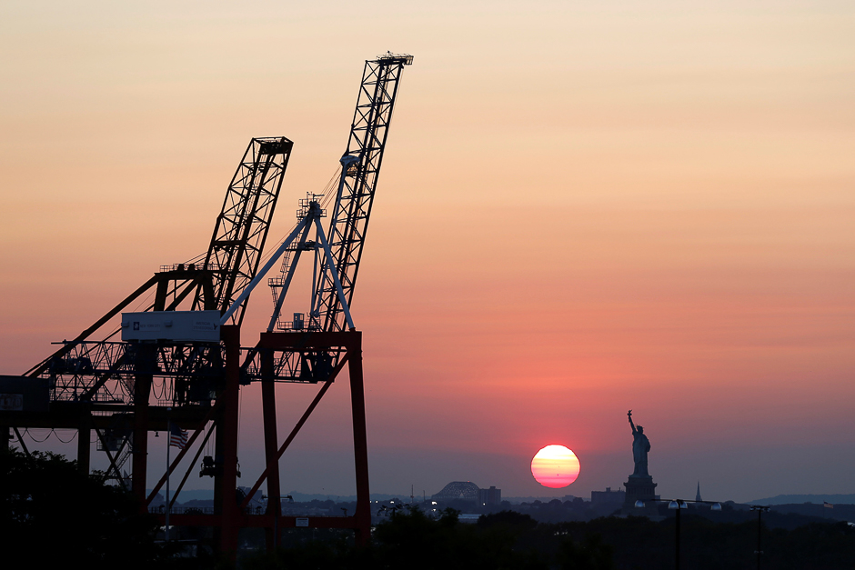 The Statue of Liberty is seen at sunset behind cranes in Brooklyn, New York, US. PHOTO: REUTERS