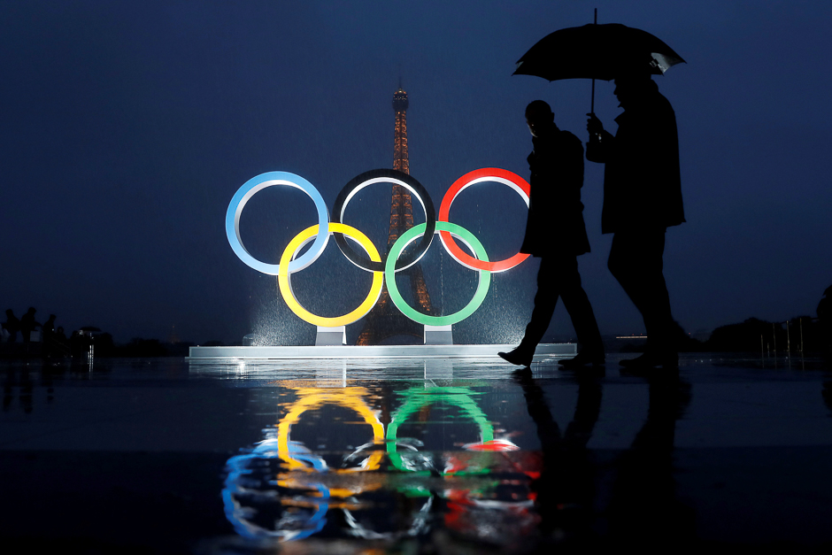 Men walk in the rain under an umbrella next to the Olympic rings after the IOC officially announced that Paris won the 2024 Olympic bid during a ceremony at the Trocadero square near the Eiffel Tower in Paris, France. PHOTO: REUTERS