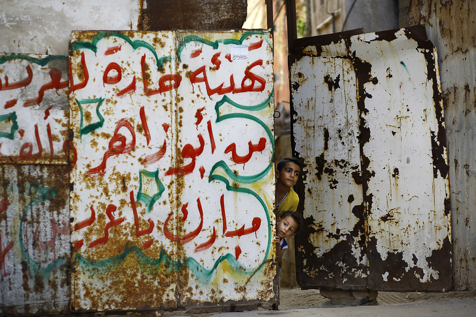 Palestinian children look out from behind the door of their house in Gaza City. PHOTO: AFP