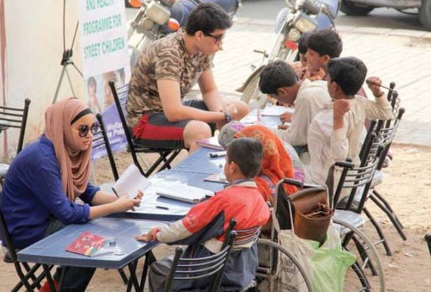 Shireen and Hassan teaching street children at an empty plot near Cafe Clifton. PHOTO: EXPRESS