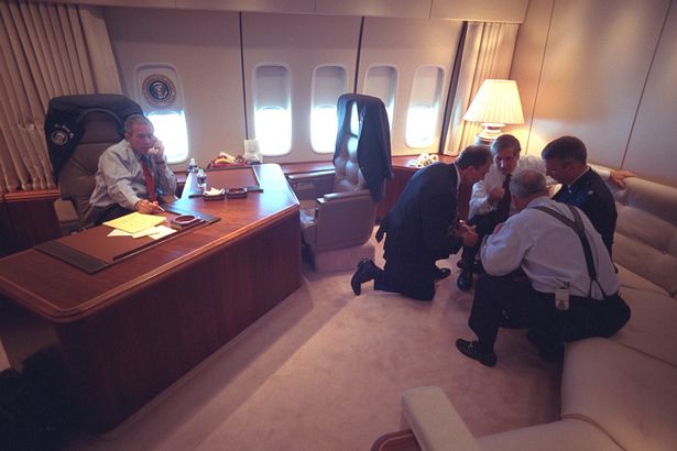President George W. Bush talks on the telephone Sept. 11, 2001, as senior staff huddle aboard Air Force One. PHOTO: George W. Bush Presidential Library
