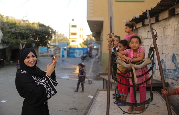 Palestinian Fatma Abu Musabbeh, 21, uses her mobile phone to take pictures of children for her social media account in Deir al-Balah in the central Gaza strip. PHOTO: AFP