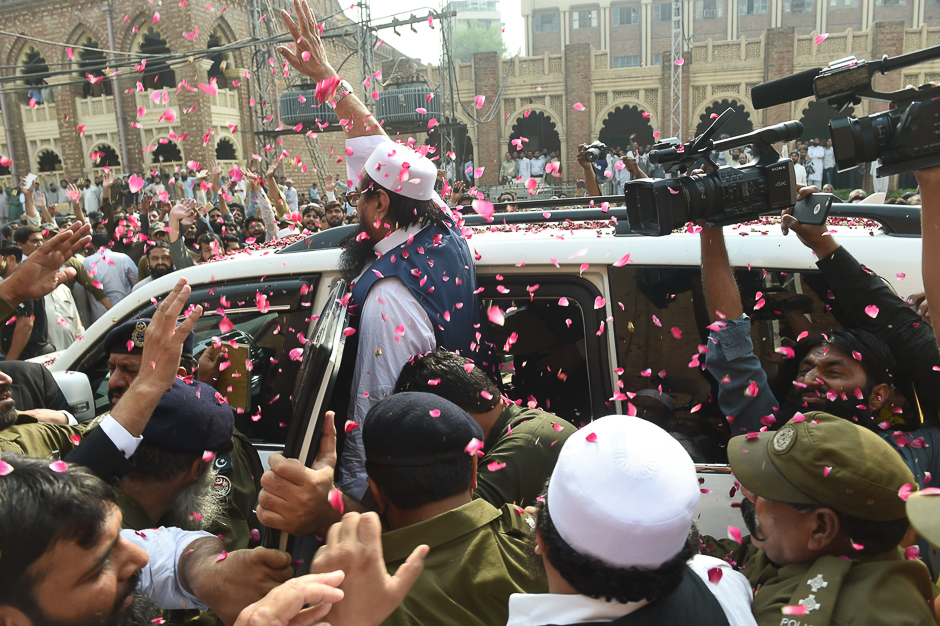 Pakistani policemen and supporters of the Jamaat-ud-Dawa (JuD) organisation gather around the car carrying leader Hafiz Saeed as he arrives at a court in Lahore. PHOTO: AFP