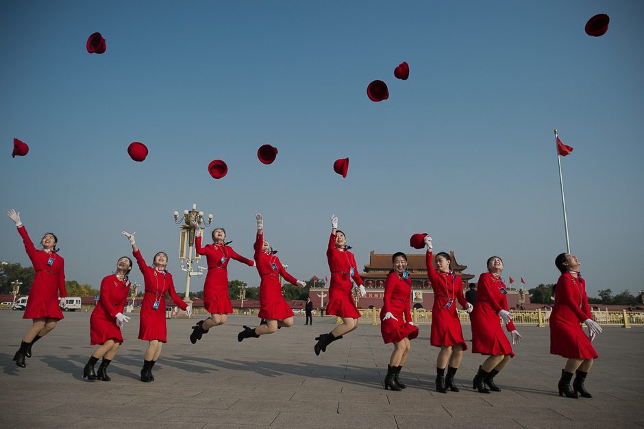 Ushers throw their hats in the air as they pose for photographers at the Tiananmen Square before the start of the closing session of the 19th National Congress of the Communist Party of China, in Beijing. PHOTO: AFP