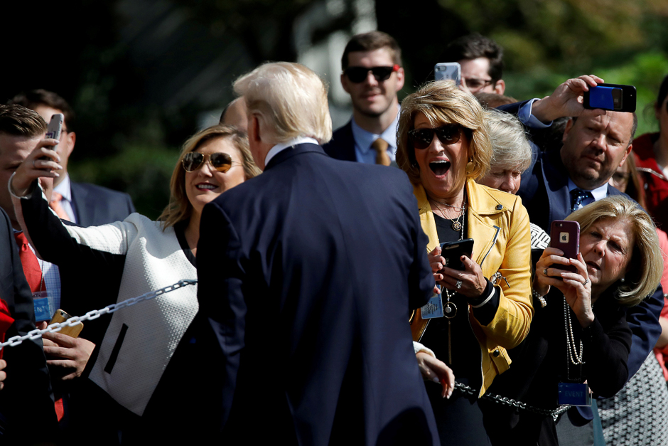 Visitors react as US President Donald Trump poses for a picture as he departs the Oval Office of the White House for Dallas, in Washington D.C., US. PHOTO: REUTERS