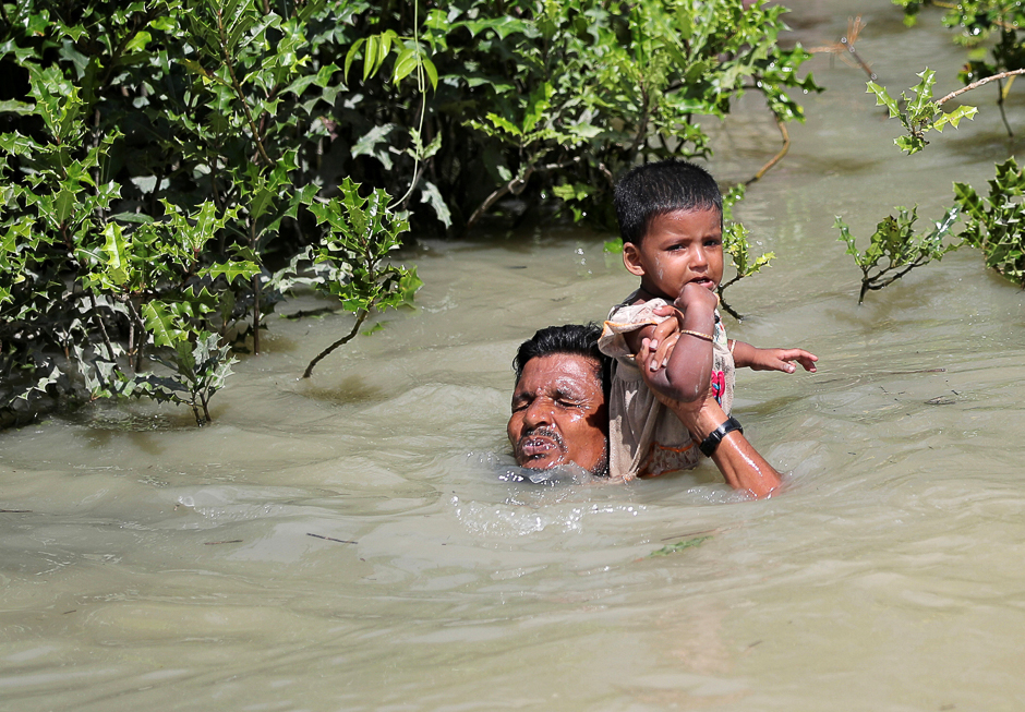 A Rohingya refugee man hols his child as he swims to cross Myanmar-Bangladesh border in Palang Khali, Bangladesh. PHOTO: REUTERS