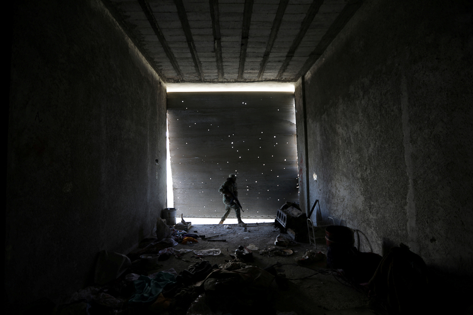 A Free Syrian Army fighter walks as he holds his weapon in a damaged shop, in the town of Tadef, Aleppo Governorate, Syria. PHOTO: REUTERS