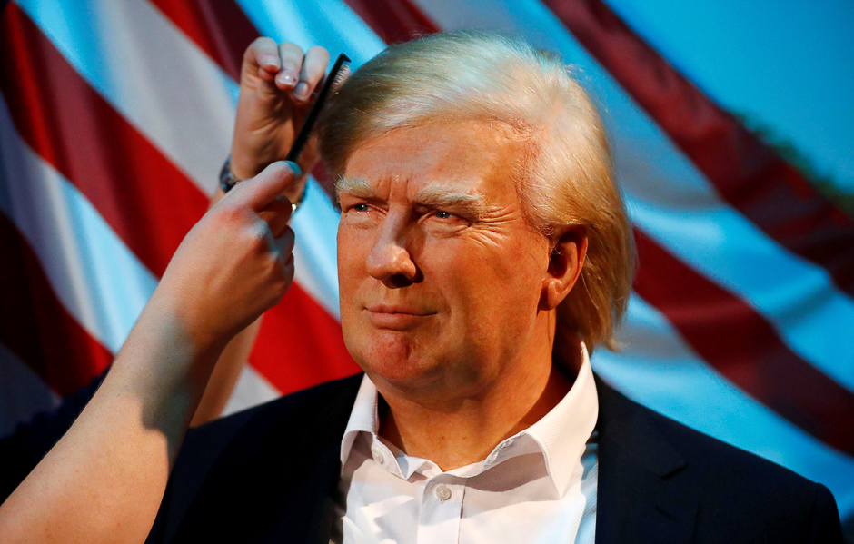 A gallery assistant poses as she pretends to put finishing touches to the hair and make-up of a waxwork of US. President Donald Trump in the Madame Tussauds wax museum in Berlin, Germany. PHOTO: REUTERS