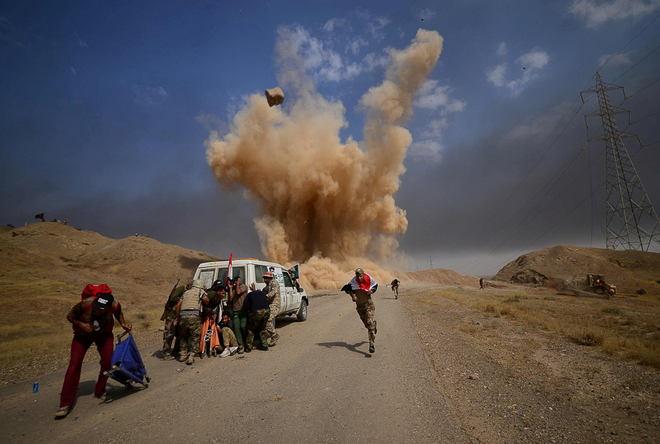 Shia Popular Mobilisation Forces (PMF) run and cover themselves from a bomb attack in outside of Hawija, Iraq. PHOTO: REUTERS