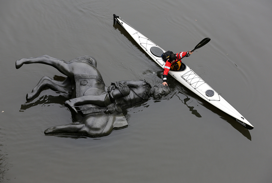 A replica equestrian statue of King Edward VII is nudged into position by Jon McCurley of art duo Life Of A Craphead, allowing it to float down the Don River during a performance in Toronto, Ontario, Canada. PHOTO: REUTERS