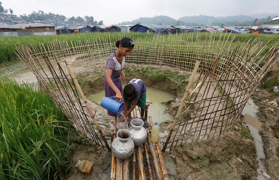 Rohingya refugee children collect water from a shallow well, dug from the sand outside their shelter at Uchiprang refugee camp near Cox's Bazar, Bangladesh. PHOTO: REUTERS