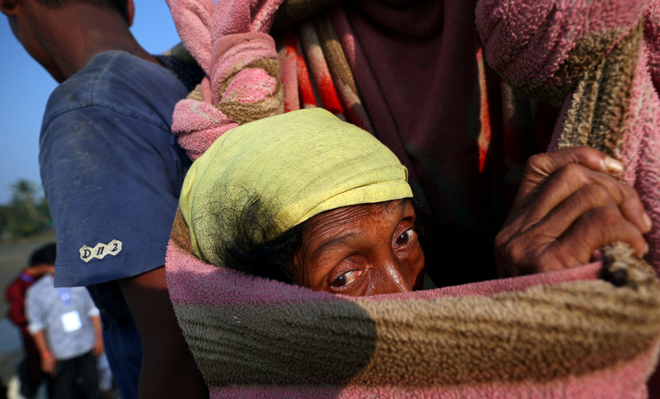 Nurij, 65, an exhausted Rohingya refugee woman is carried by fellow villagers to a port after crossing from Myanmar, in Teknaf, Bangladesh. PHOTO: REUTERS