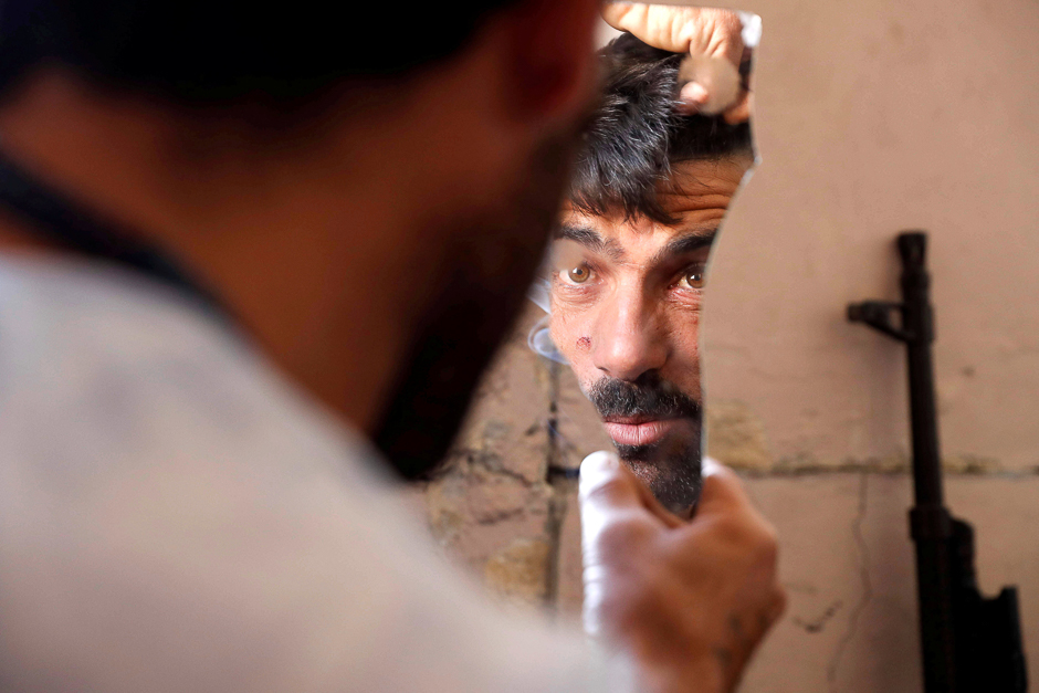 A fighter of Syrian Democratic Forces fixes his hair using a broken mirror at the frontline in Raqqa, Syria. PHOTO: REUTERS