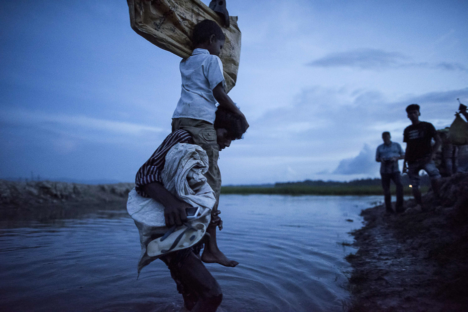 Rohingya refugees wade after crossing the Naf river from Myanmar into Bangladesh in Whaikhyang. PHOTO: REUTERS