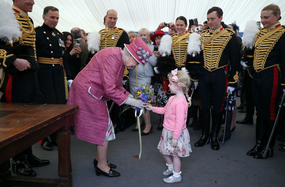 Britain's Queen Elizabeth II receives a posy from Tilly Beau Wildish during a reception following The King's Troop Royal Horse Artillery (KTRHA), commonly known as the 'Gunners', 70th Anniversary parade at Hyde Park in central London. PHOTO: AFP