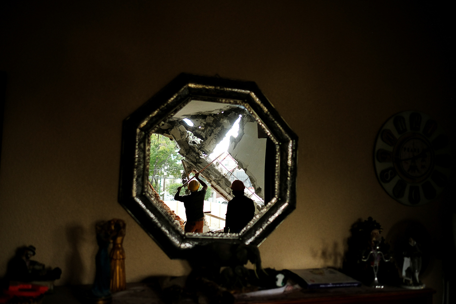 Workers are reflected on a mirror as they work inside a collapsed house, after an earthquake in Mexico City, Mexico. PHOTO: REUTERS