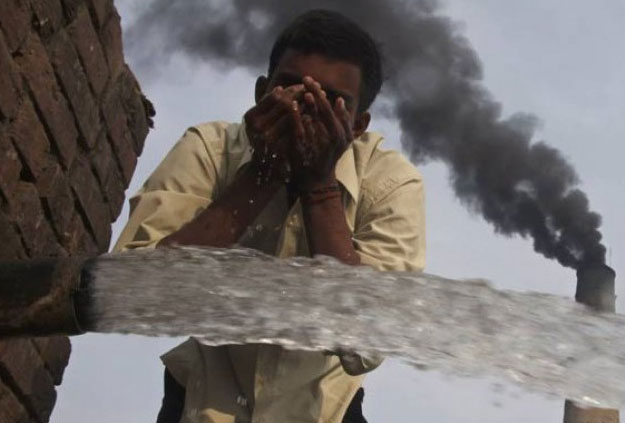 A labourer drinks water as smokes rise from a chimney of a brick factory. PHOTO REUTERS