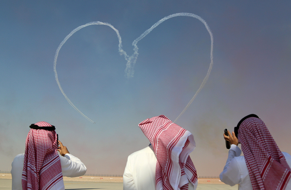 Visitors take pictures as Al Fursan aerobatic team of the United Arab Emirates Air Force performs during the Dubai Airshow in Dubai, UAE. PHOTO: REUTERS