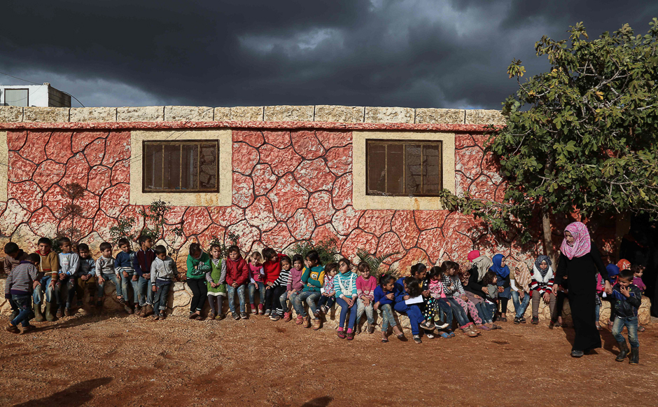 Syrian children who lost their parents in the fighting sit outside an orphanage with a counsellor situated near the town on Sarmada close to the Syria-Turkey border. PHOTO: AFP