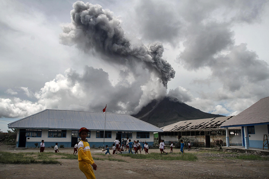 Children play at an elementary school as the Mount Sinabung volcano spews smoke in Karo. PHOTO: AFP