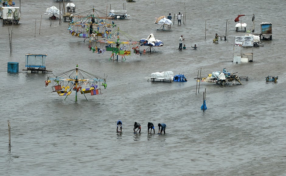 People walk through a flooded area of Marina Beach on the Bay of Bengal coast after heavy rains in Chennai. PHOTO: AFP