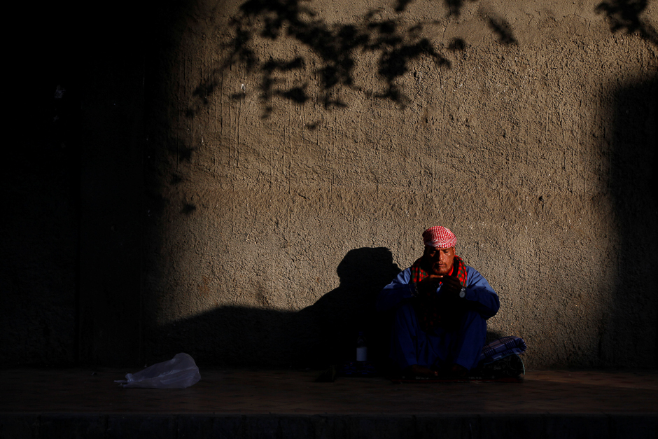 A man sits in the sunlight to warms himself along a side walk in the early morning in Karachi. PHOTO: REUTERS