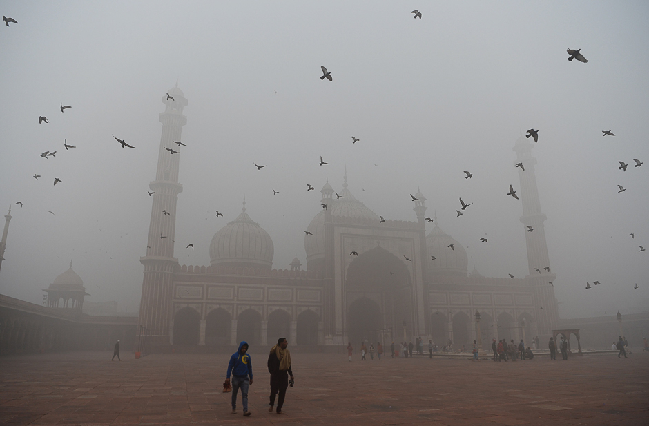 Indian visitors walk through the courtyard of Jama Masjid amid heavy smog in the old quarters of New Delhi. PHOTO: AFP